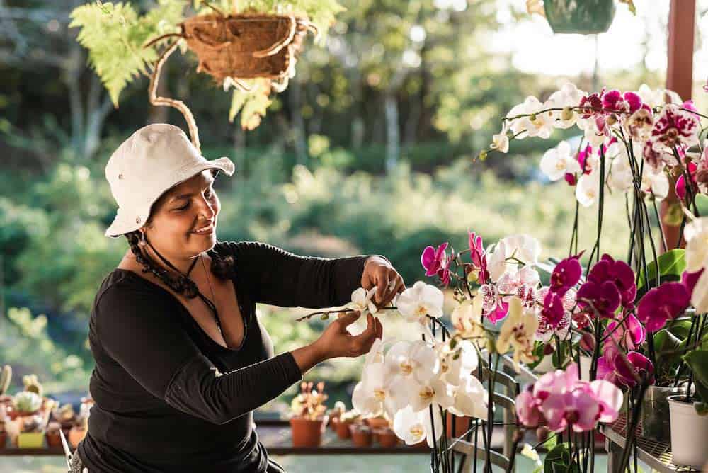 A happy woman tending to her orchid plant