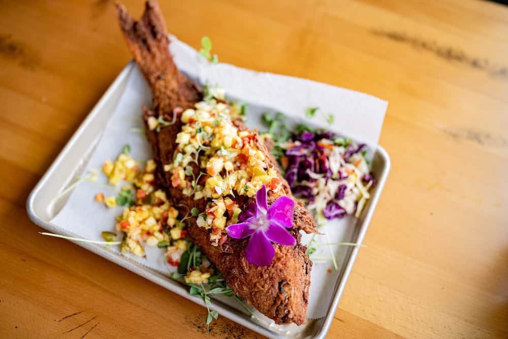 A fried fish served with an edible orchid as garnish